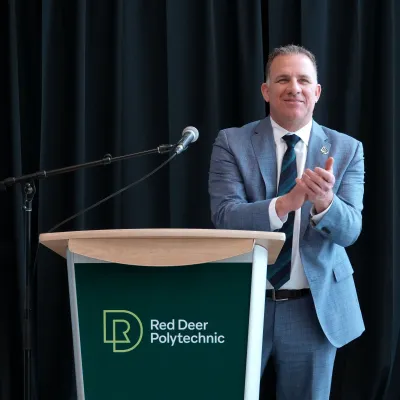 Stuart Cullum, RDP's President stands behind a podium and smiles while clapping
