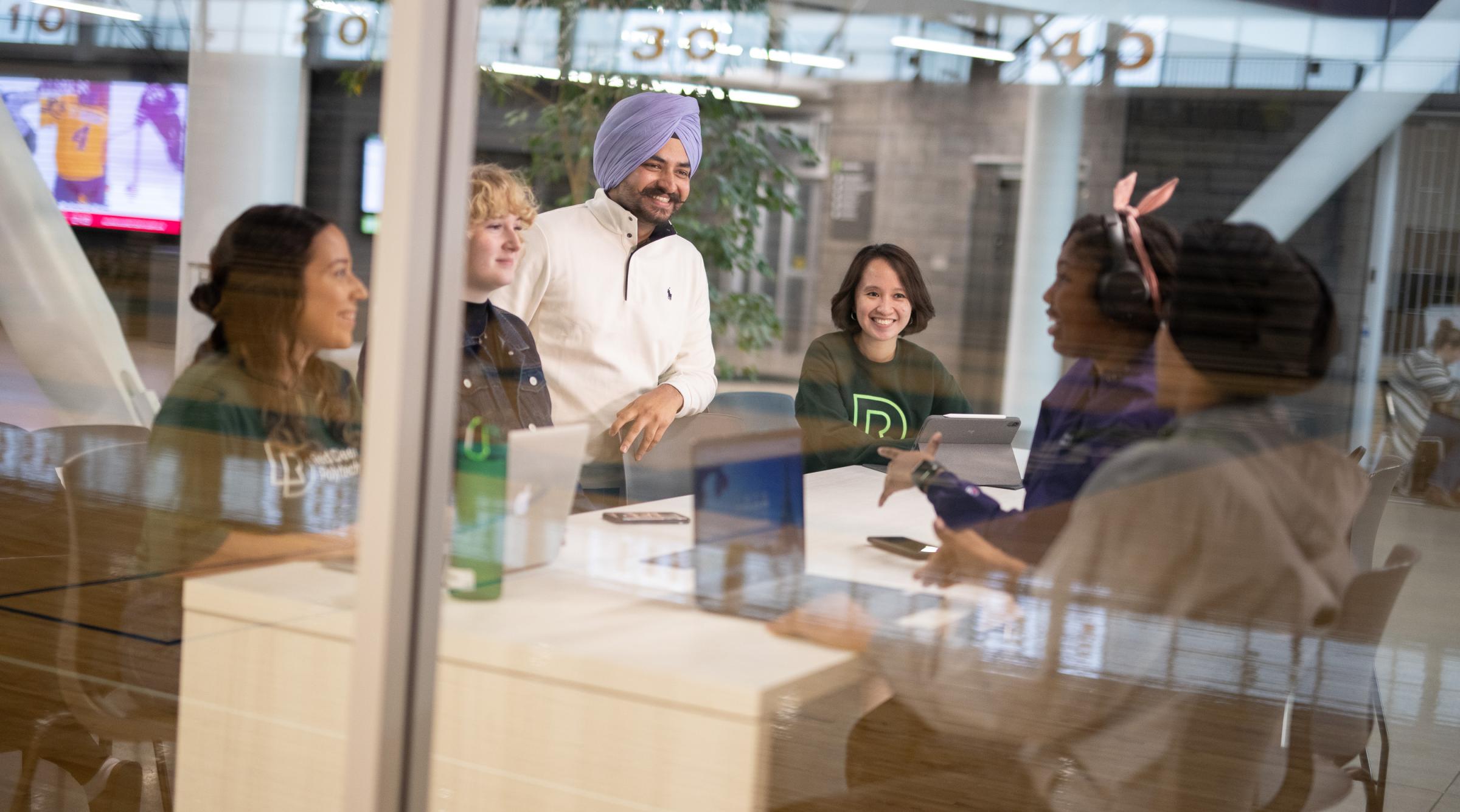 A group of diverse students sitting around a table laughing