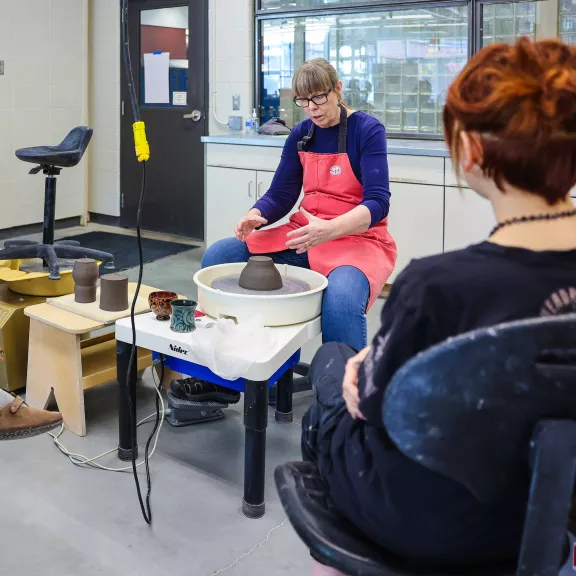 Instructor at pottery wheel instructing class