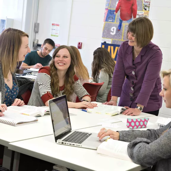 Education instructor talking with students in group project