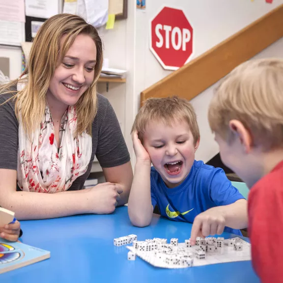 Child Care working playing a dice game with two children