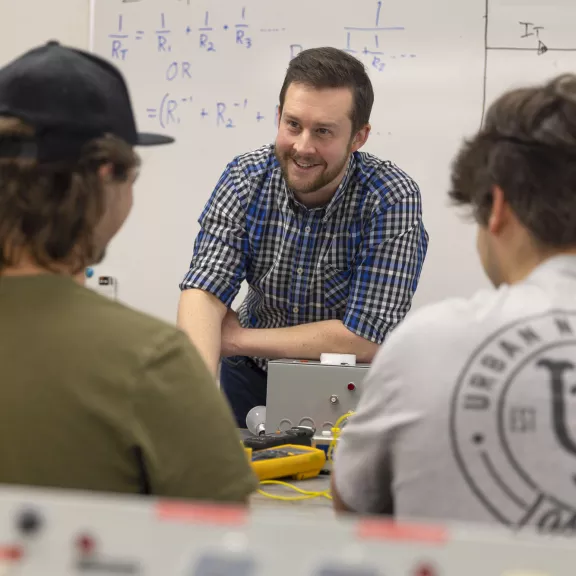 Electrical instructor talking to two students in classroom