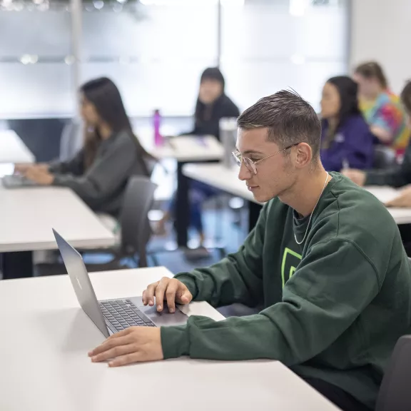 Male student working on a computer, wearing an RDP shirt