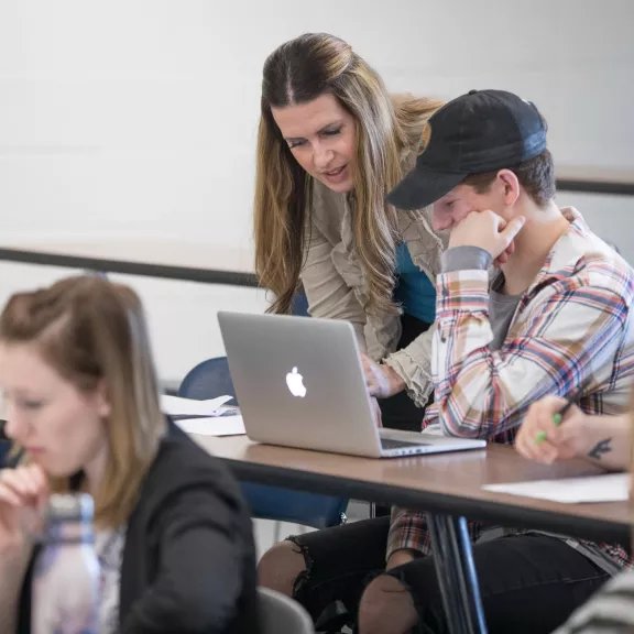 Instructor helping student in class on laptop