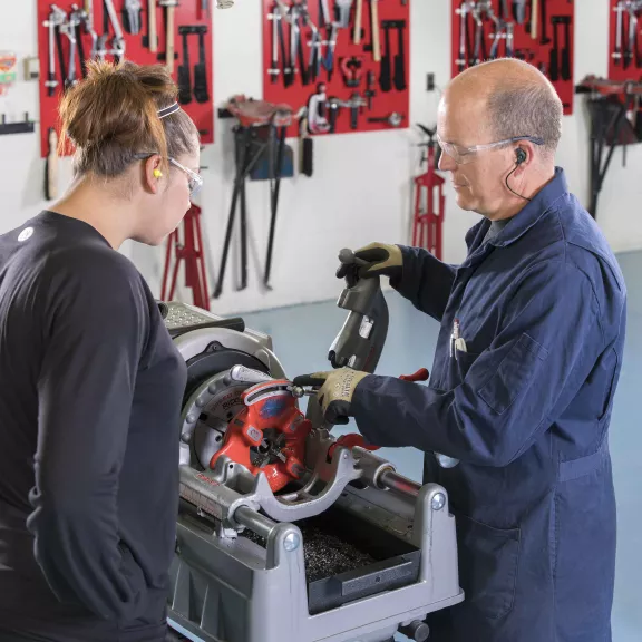 Plumbing instructor showing student equipment