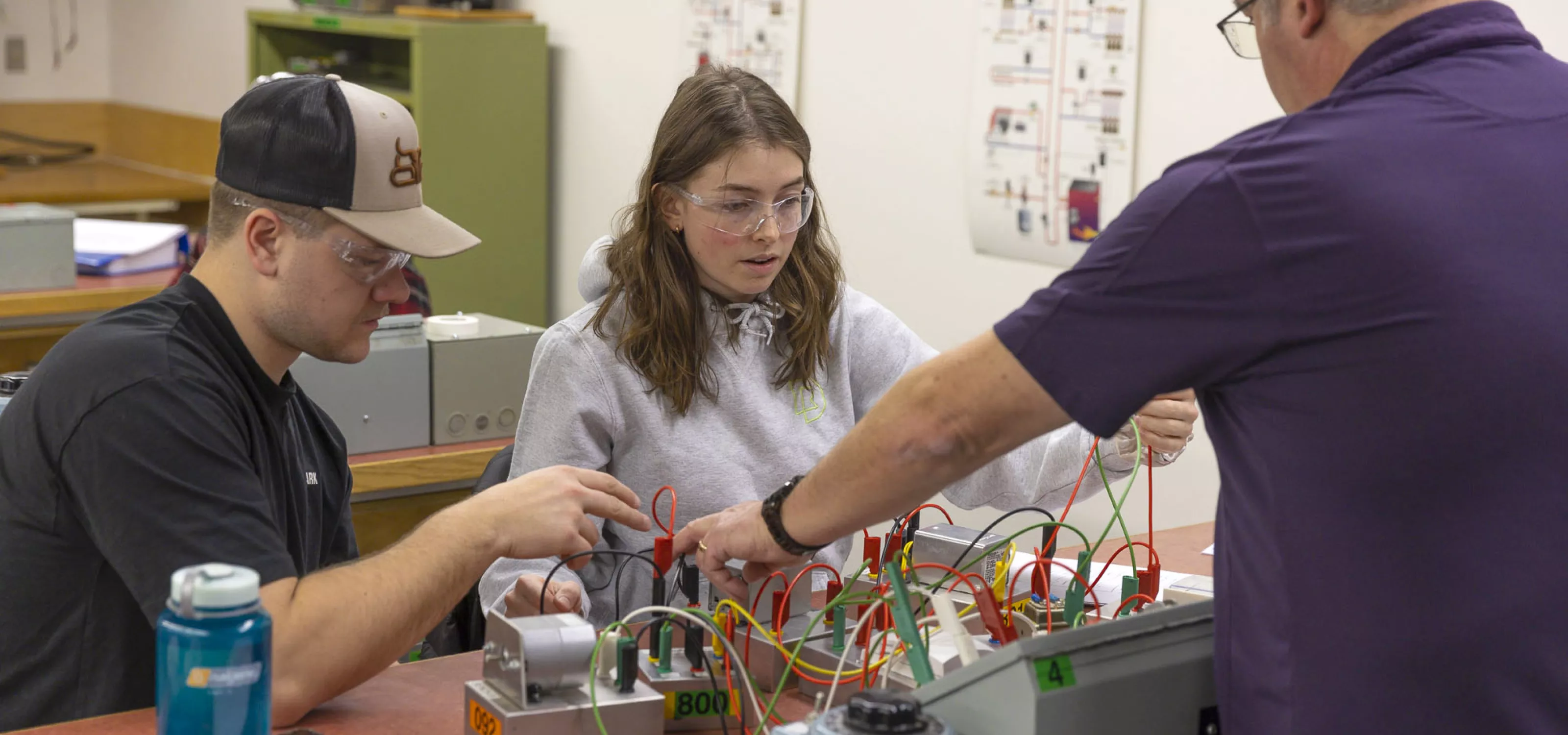 Electrical instructor hooking wires with two students