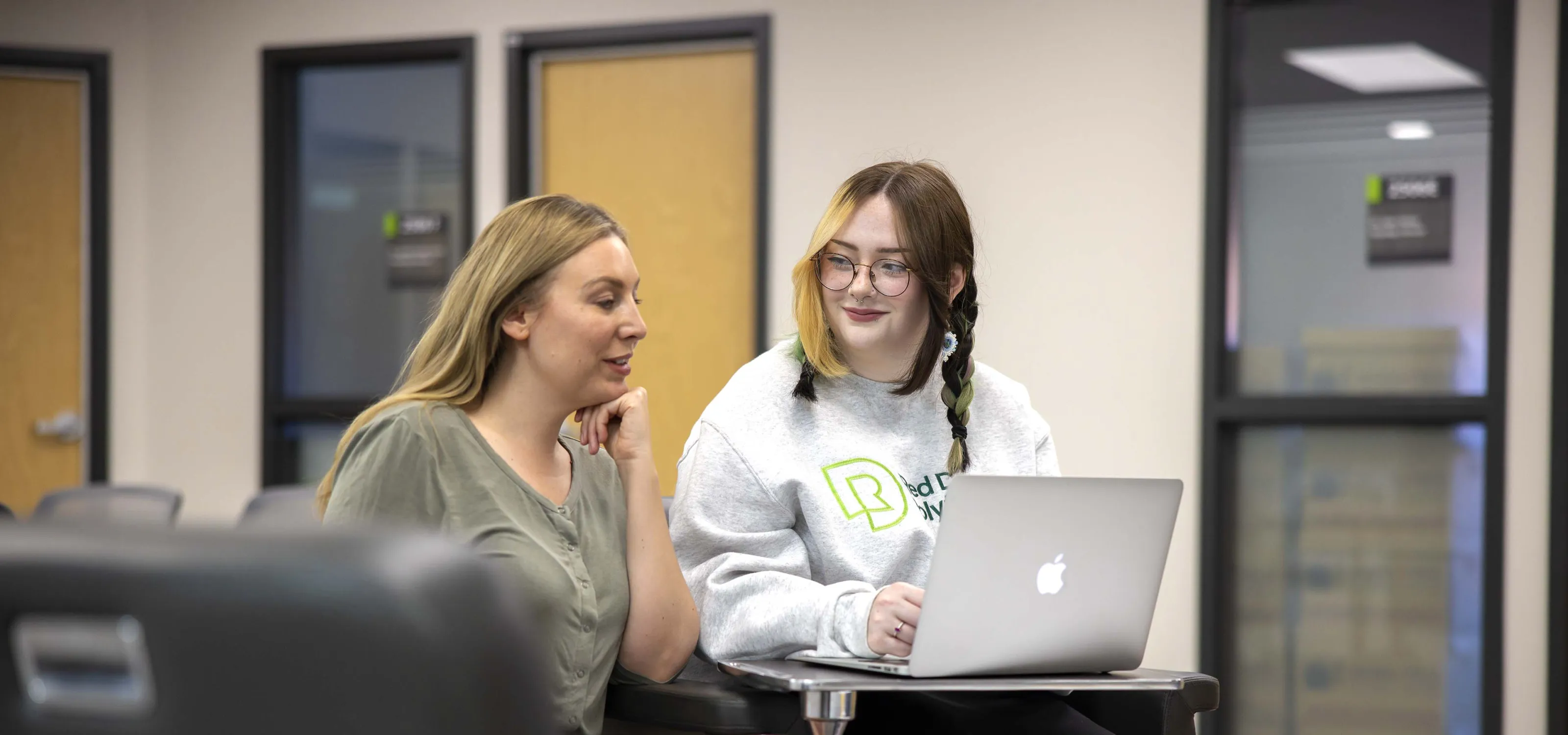 Two women sitting together with an open laptop.