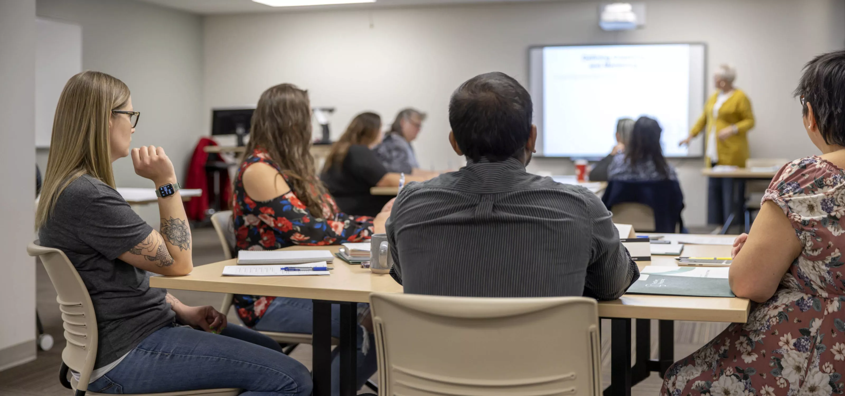 Large classroom with mature students facing the instructor at the front of class.