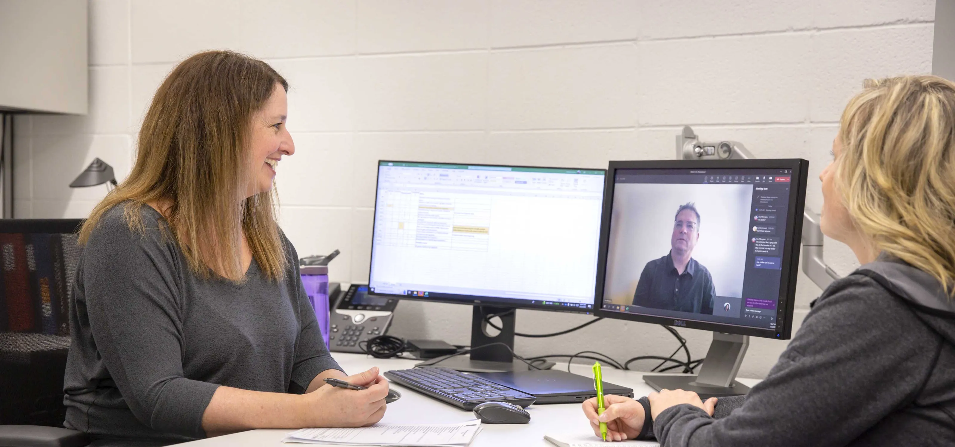Two employees meeting with a client virtually in an office